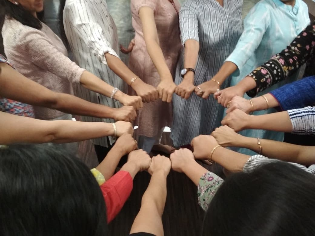 A circle of hands joined together at the centre of a group
